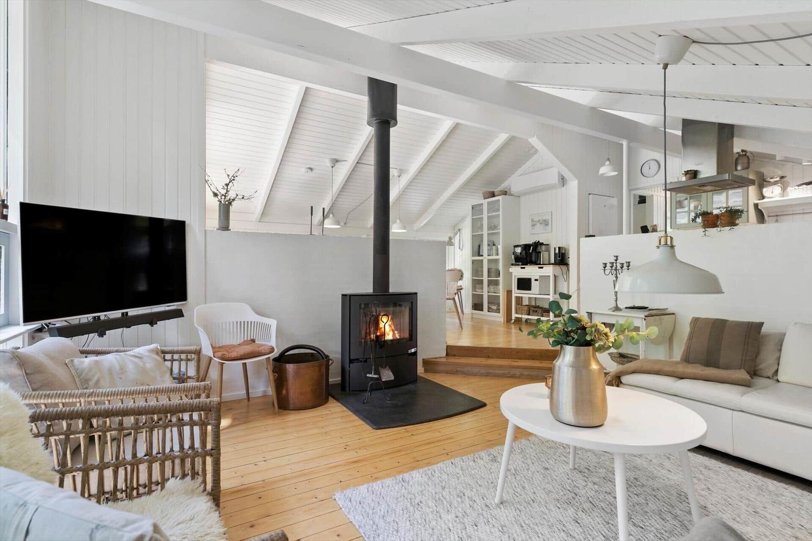 Wohnzimmer mit Kamin, Sofa und Fernseher. Holzboden und weiße Wände.