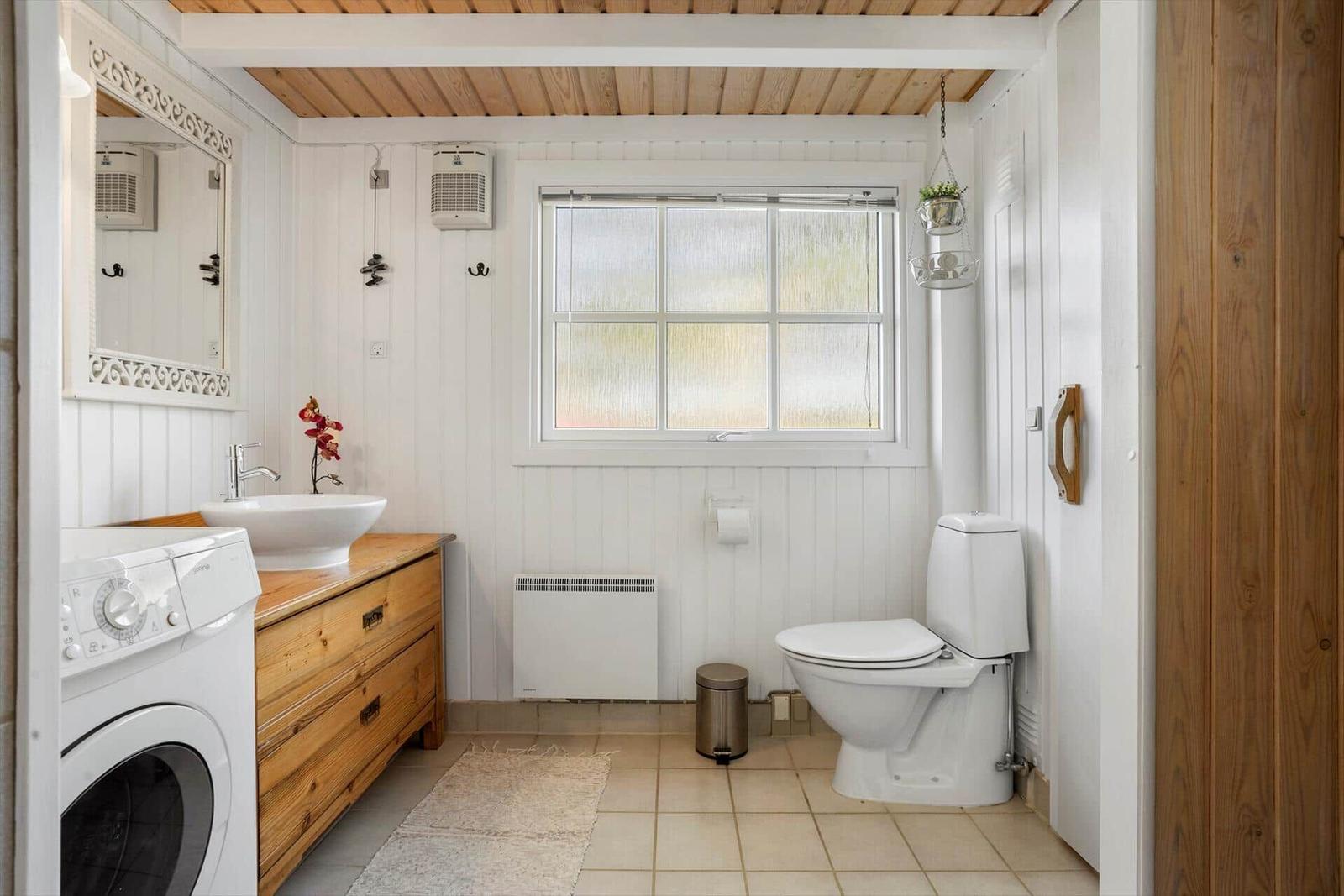 Badezimmer mit Waschmaschine, Toilette und Holzregal.