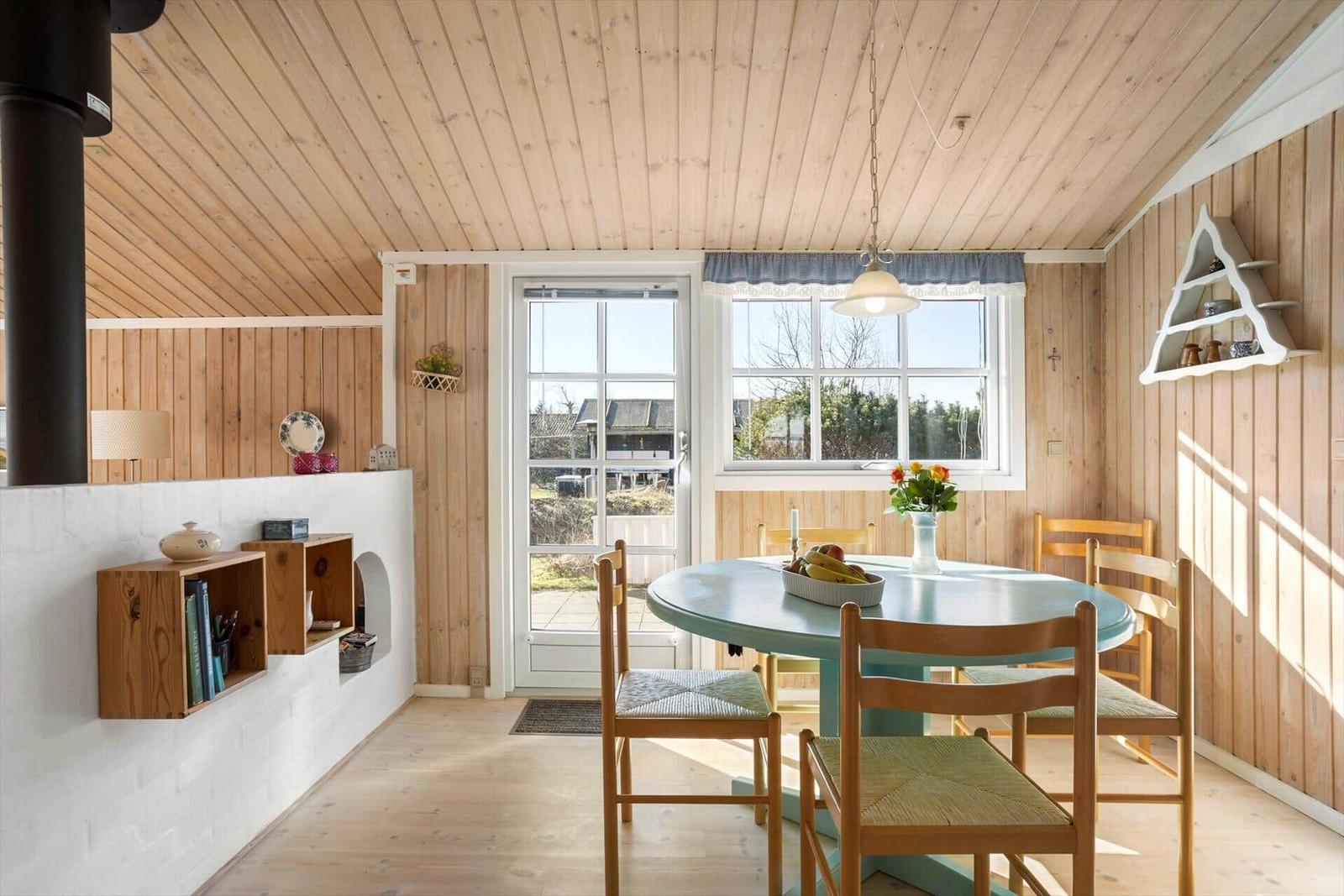 Esszimmer mit runder Tafel, Holzstühlen und Fenstern zur Aussicht.