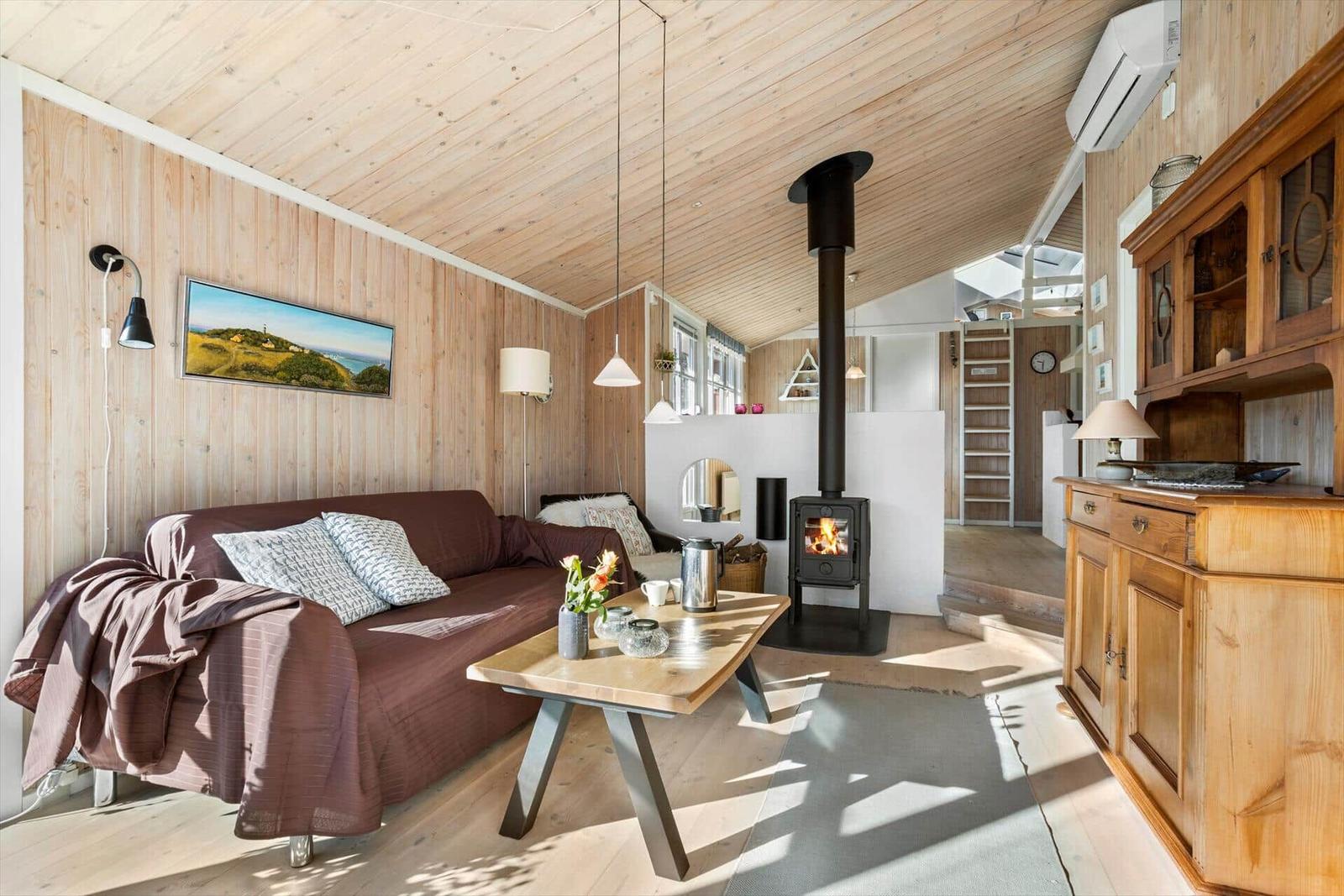Wohnraum mit Sofa, Kamin und Holzmöbeln.