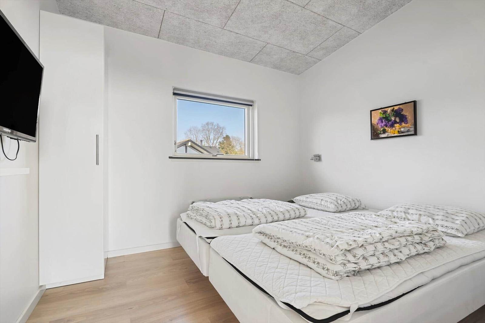 Bedroom with two beds, window, and TV mounted on the wall.