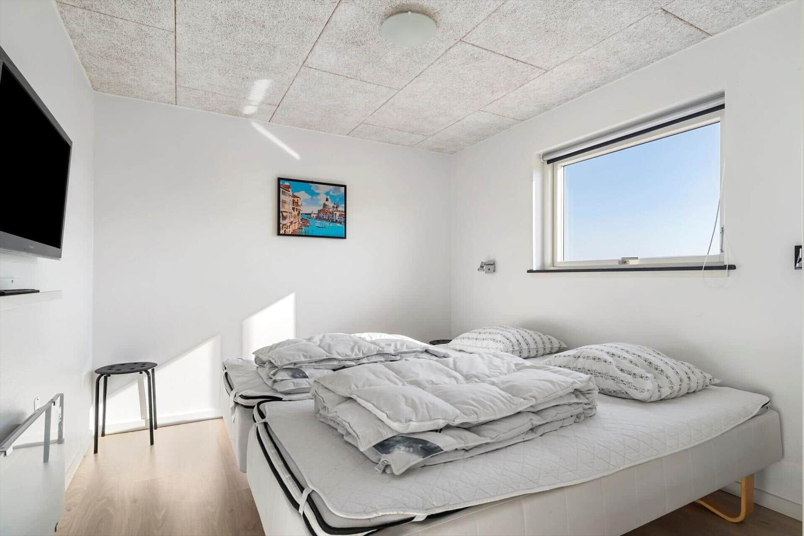 Bedroom with bed, window, and TV on the wall.