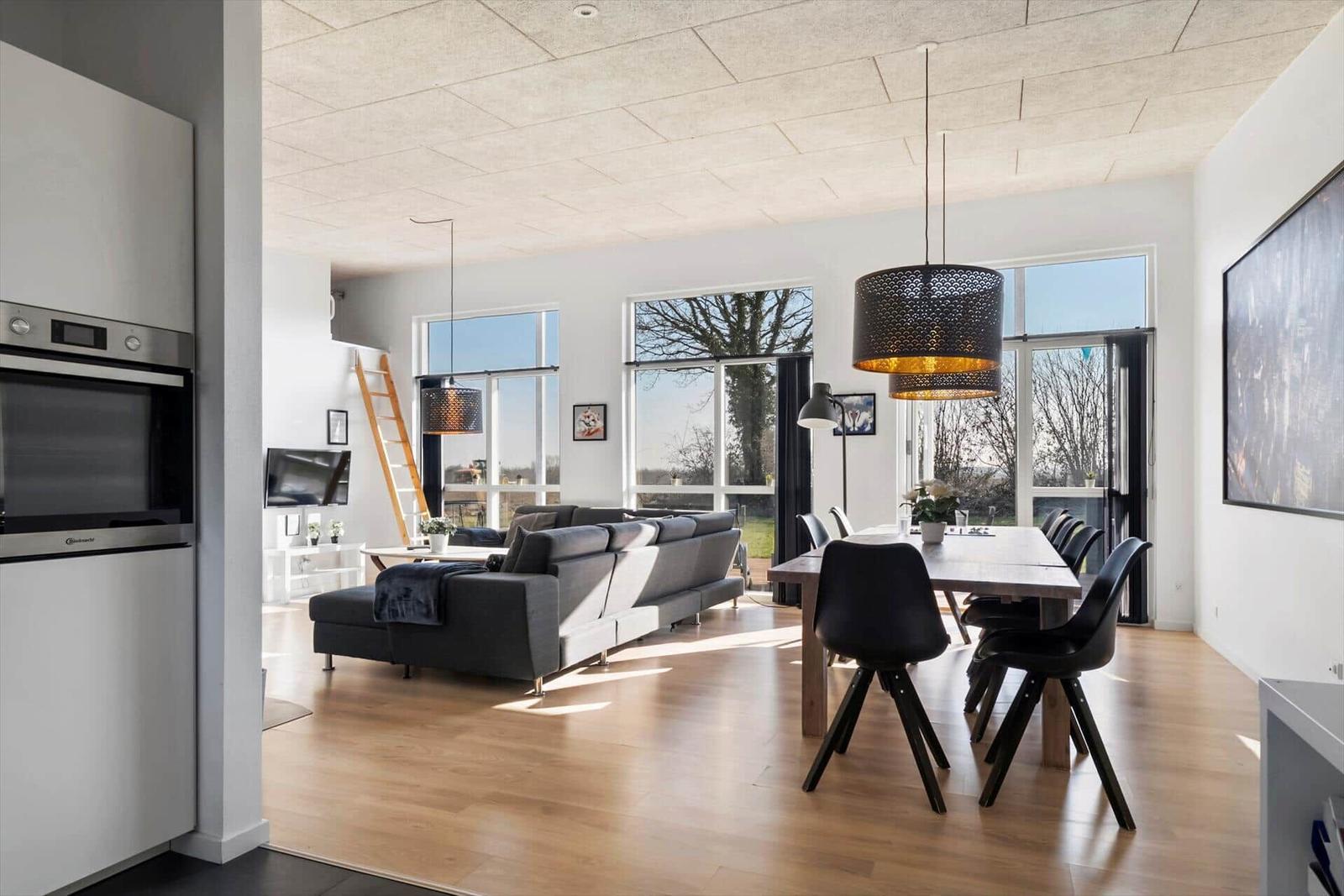 Open living and dining area with modern furniture and large windows.