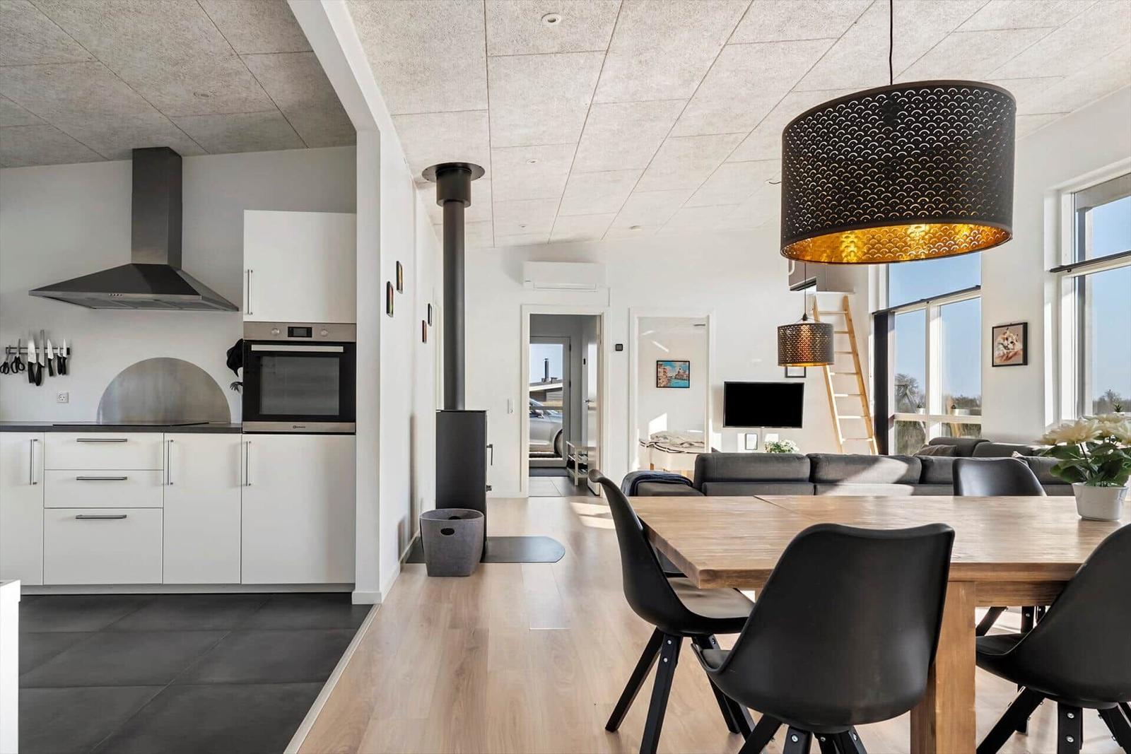 Modern kitchen with dining area and living room in background.