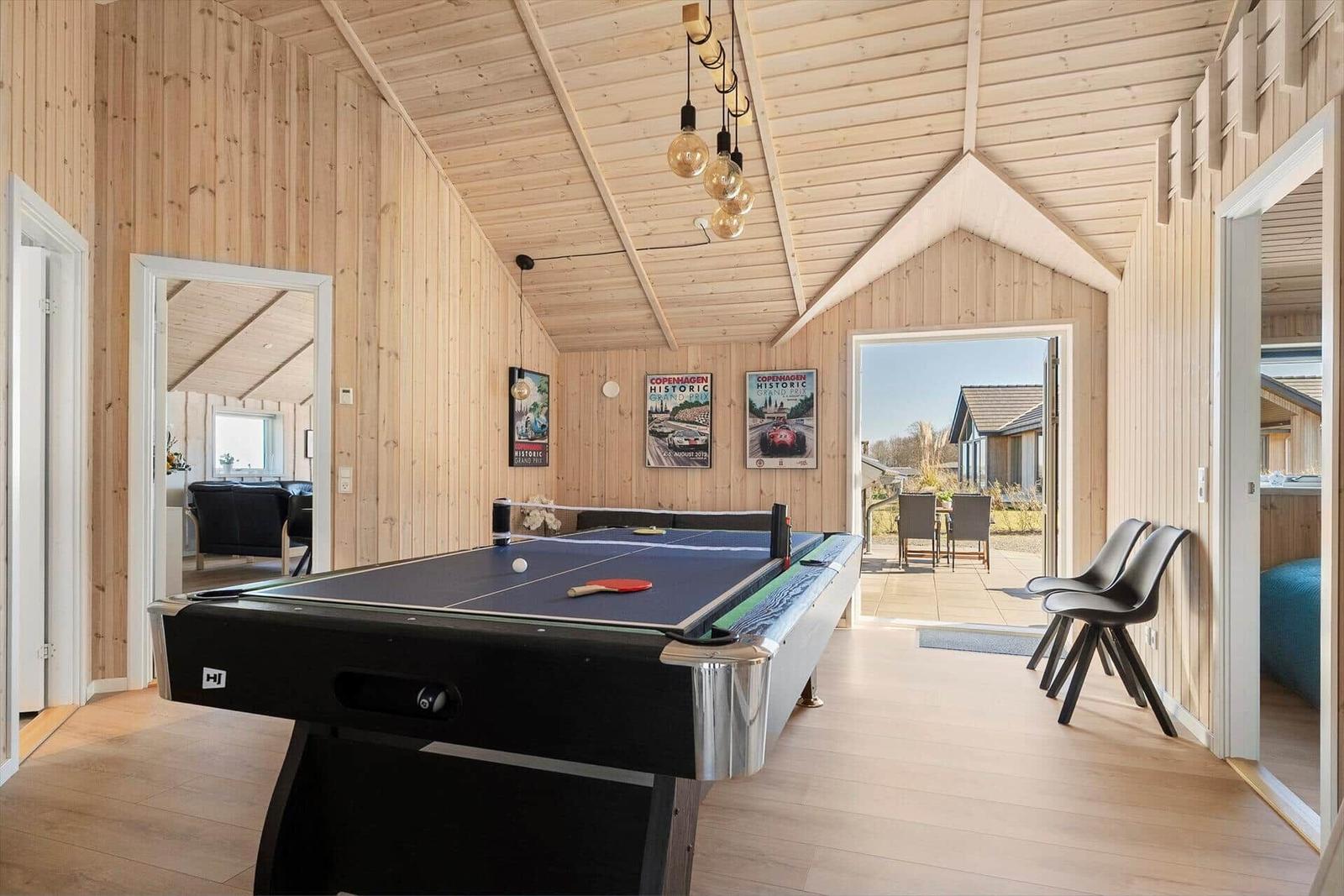 Room with ping pong table, wooden walls, and view of terrace.
