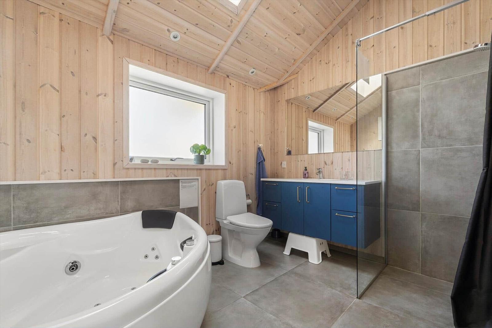 Bathroom with bathtub, shower, and blue vanity.
