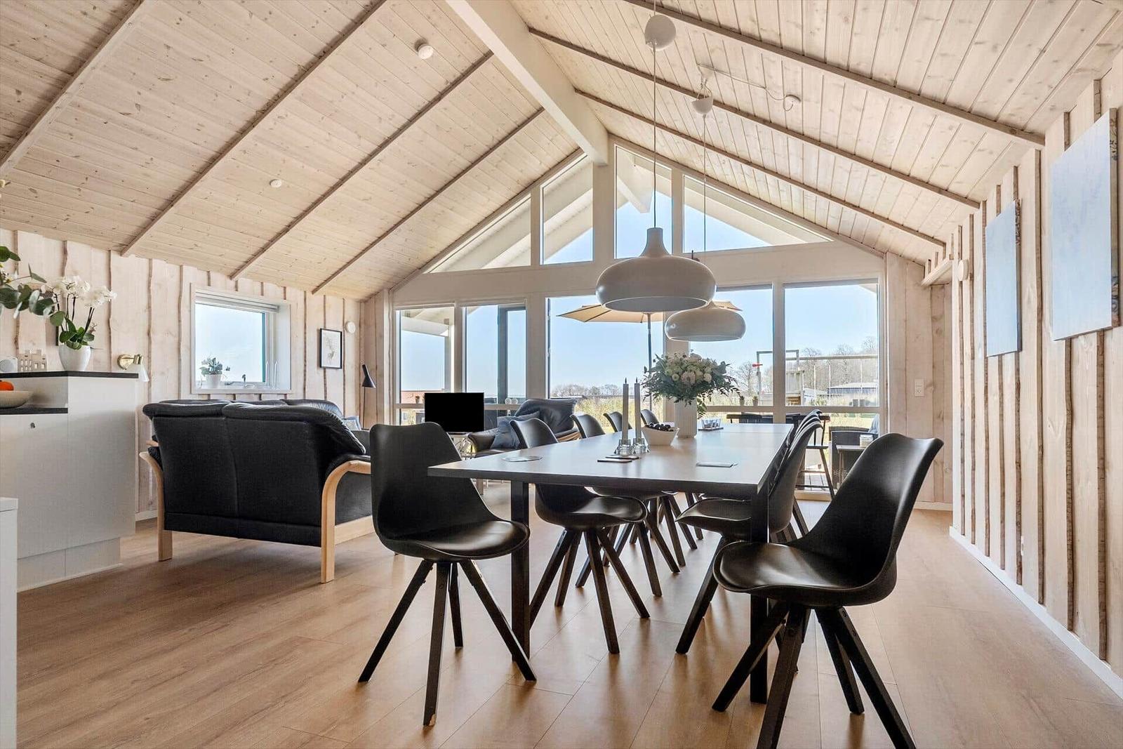 Modern dining room with wooden ceiling and large window. Table and chairs are black.