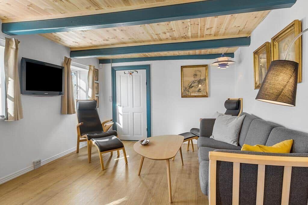 Wohnzimmer mit Sofa, Sessel und TV an der Wand.