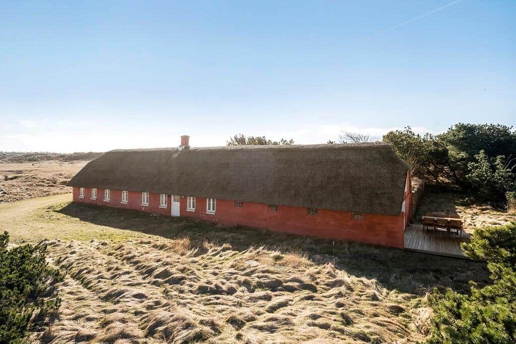 Rotes Gebäude mit strohgedecktem Dach und Terrasse in ländlicher Umgebung