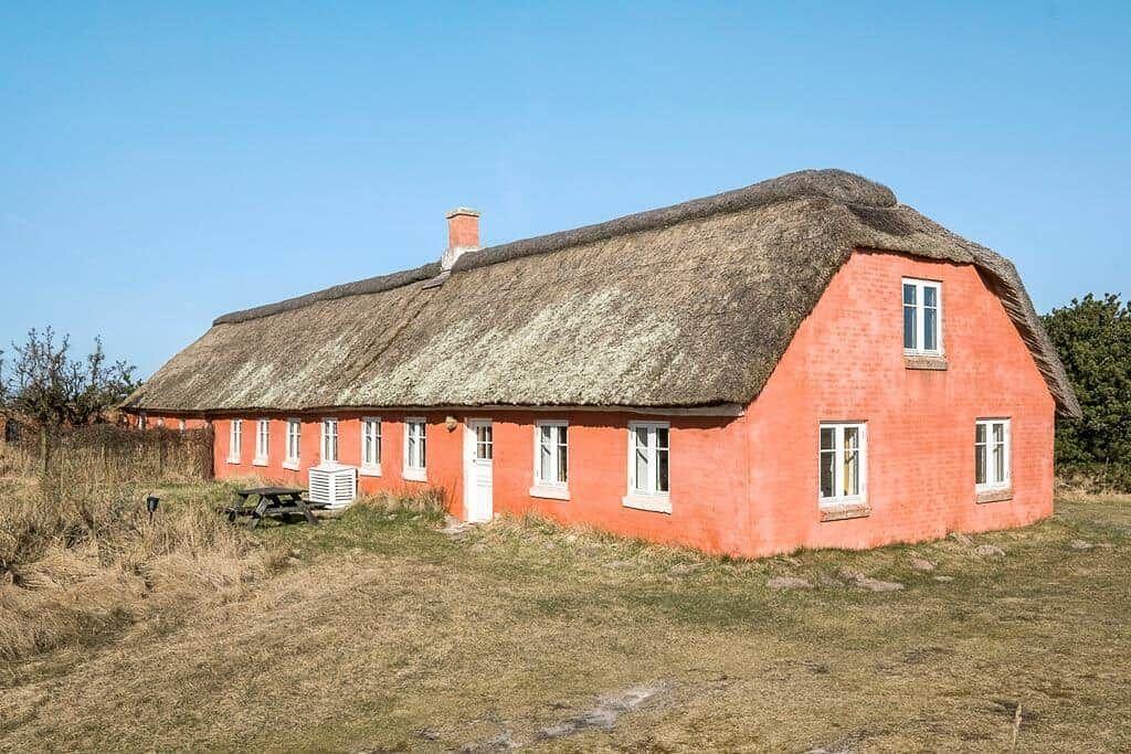 Rotes Gebäude mit Strohdach und weißen Fenstern in ländlicher Umgebung