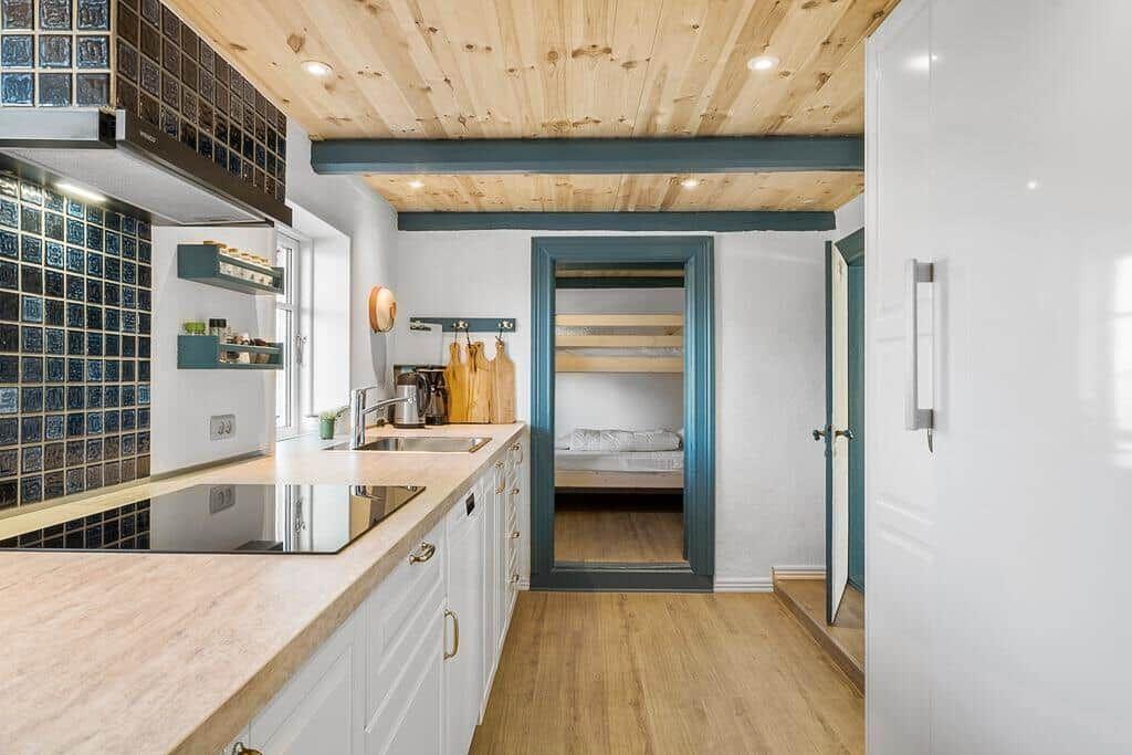Küche mit Holzdecke und Blick in Schlafzimmer mit Bett.