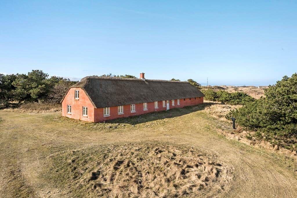 Rotes Haus mit Strohdach auf grüner Wiese