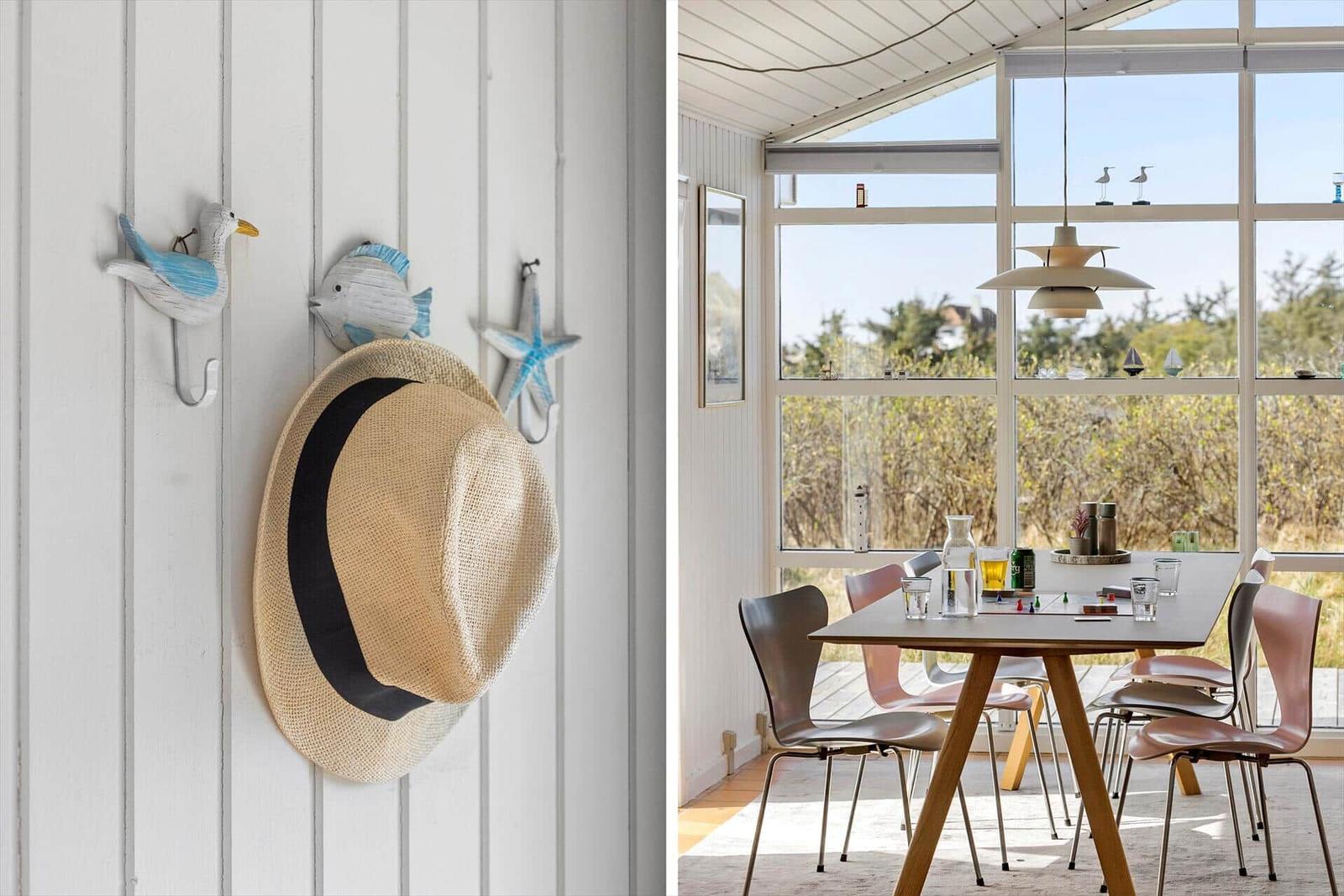 Hut an Wandhalterungen, Essbereich mit Tisch und Stühlen, großes Fenster mit Blick auf Garten.