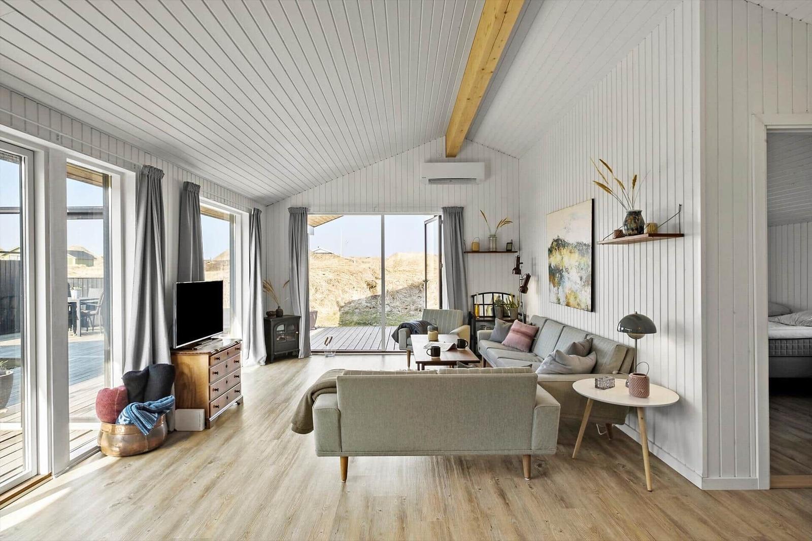 Wohnraum mit Sofa, Fernseher und großem Fensterblick.