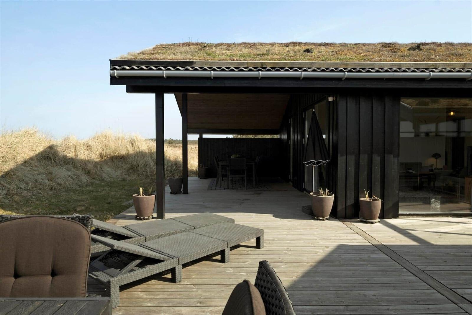 Terrasse mit Liegen und Blick auf Grasdachhaus