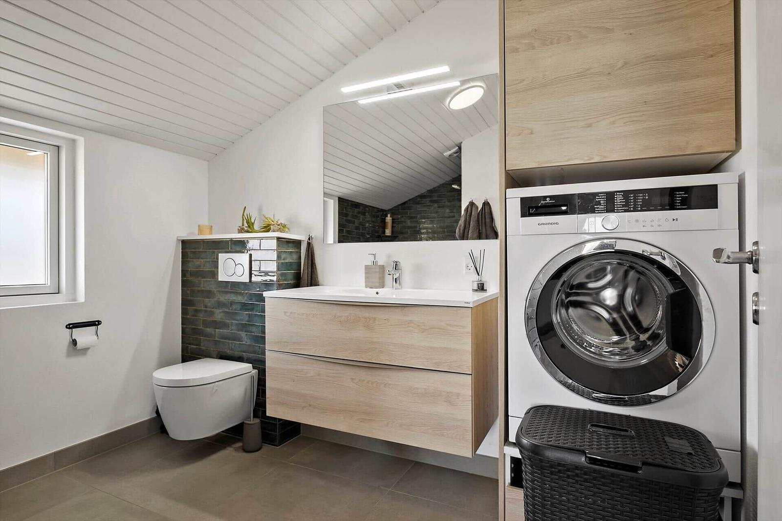 Badezimmer mit Waschmaschine, Waschtisch und Toilette