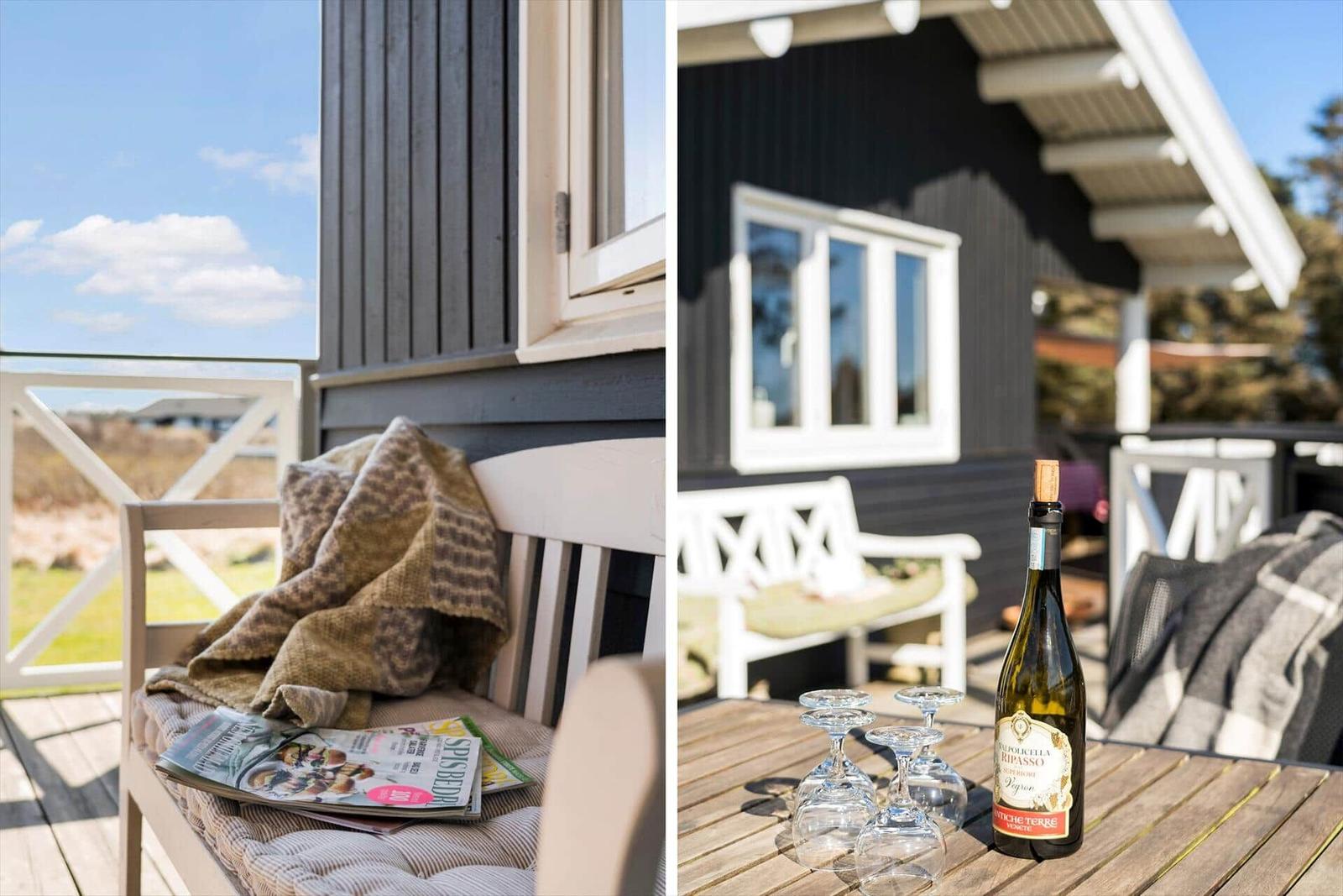 Terrasse mit Stuhl, Decke und Zeitschrift. Tisch mit Weinflasche und Gläsern.