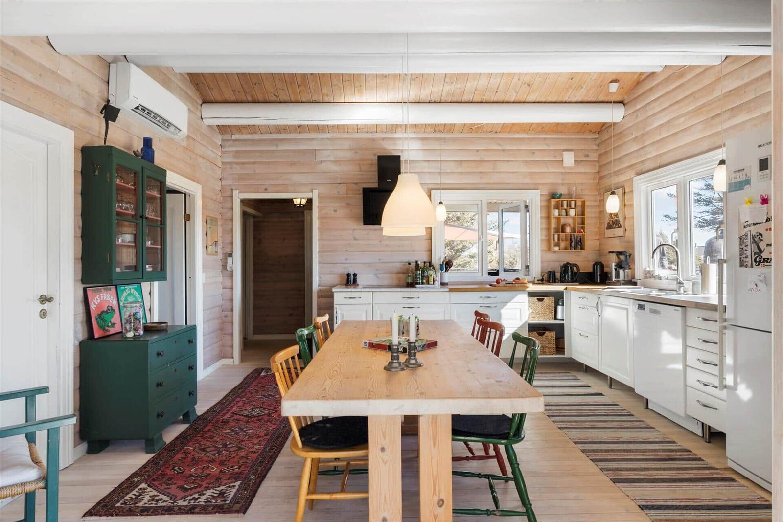Essbereich mit Holztisch, Stühlen und Küche in Holzhaus.