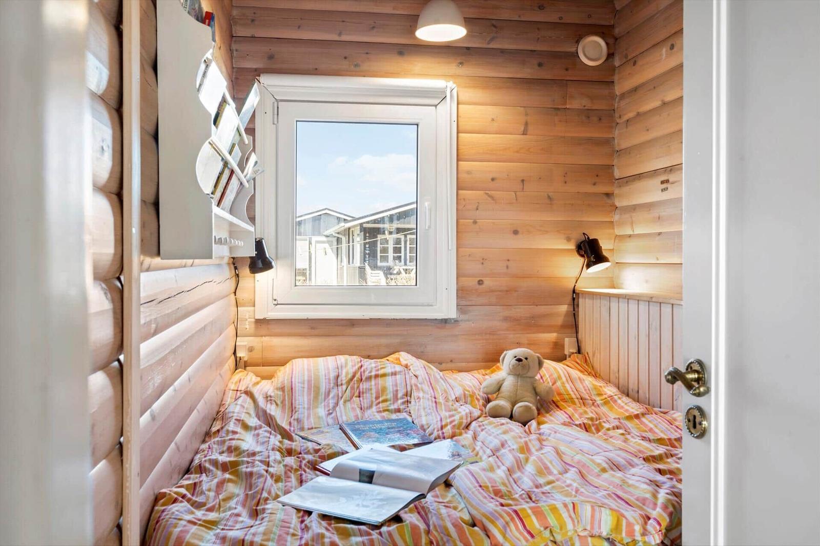 Schlafzimmer mit Holzwand, Fenster und Teddybär auf Bett