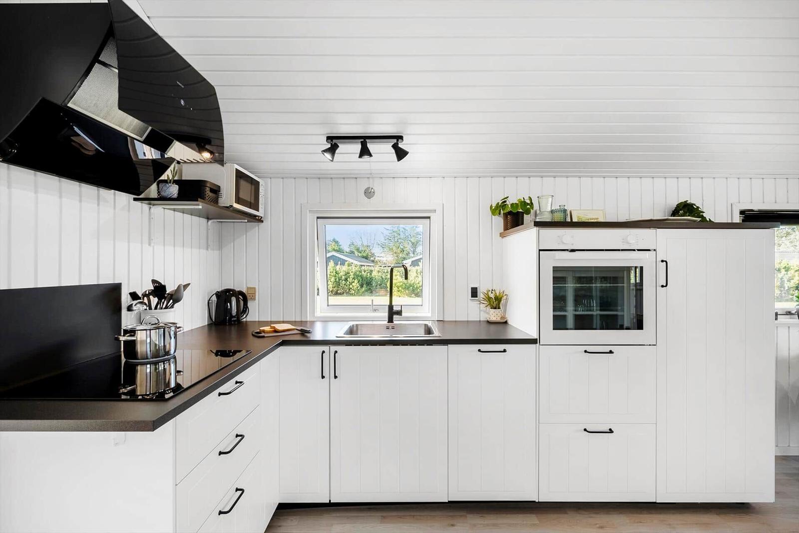 Kitchen with white cabinets, black countertop, and window to the garden.