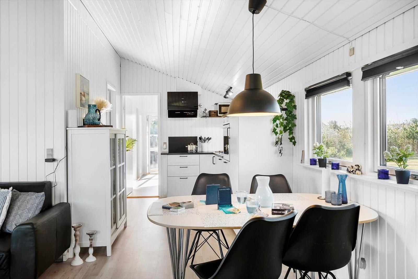 Dining area with table, chairs, and garden view. Kitchen and living area visible.