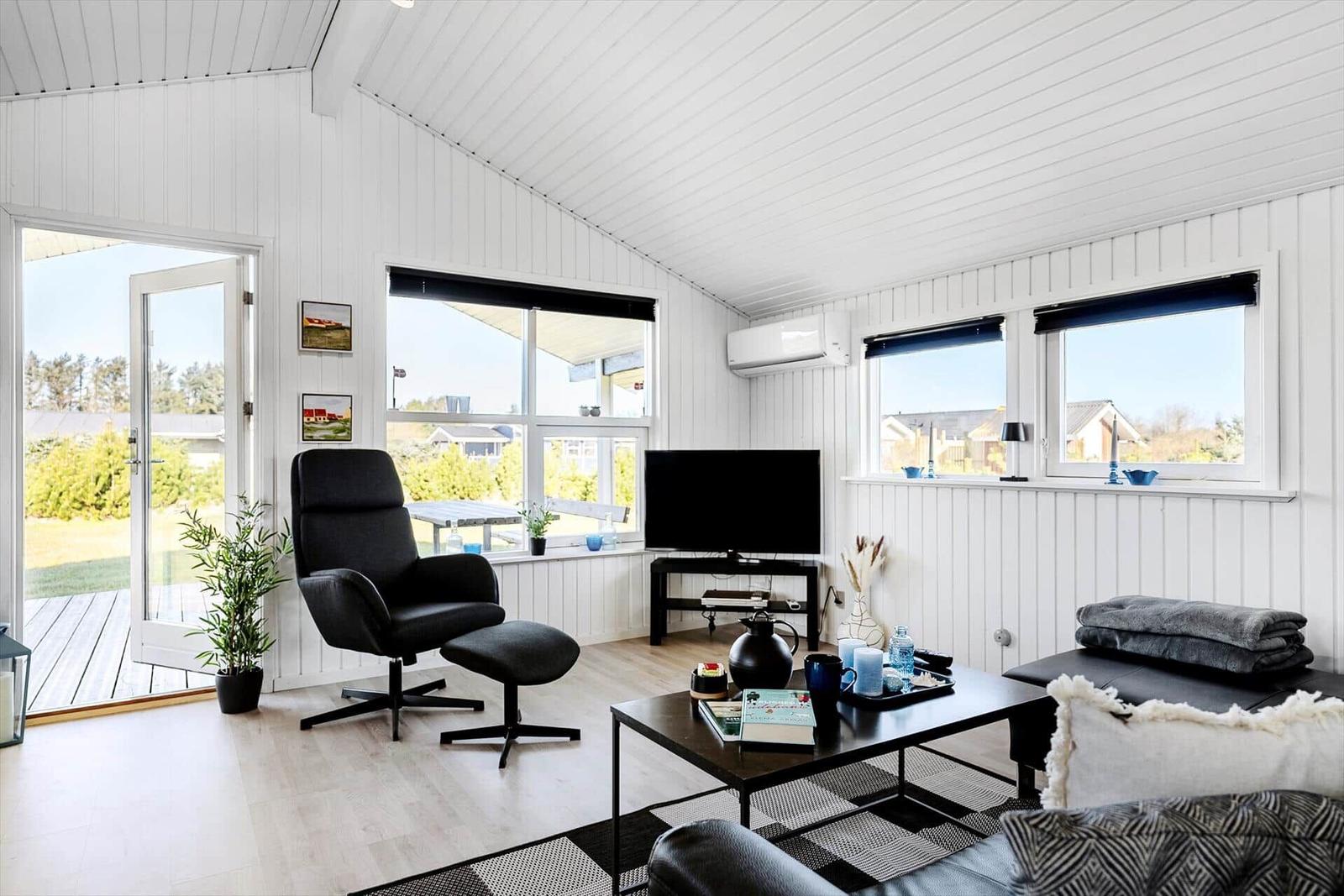 Living room with TV, seating, and view of the terrace.