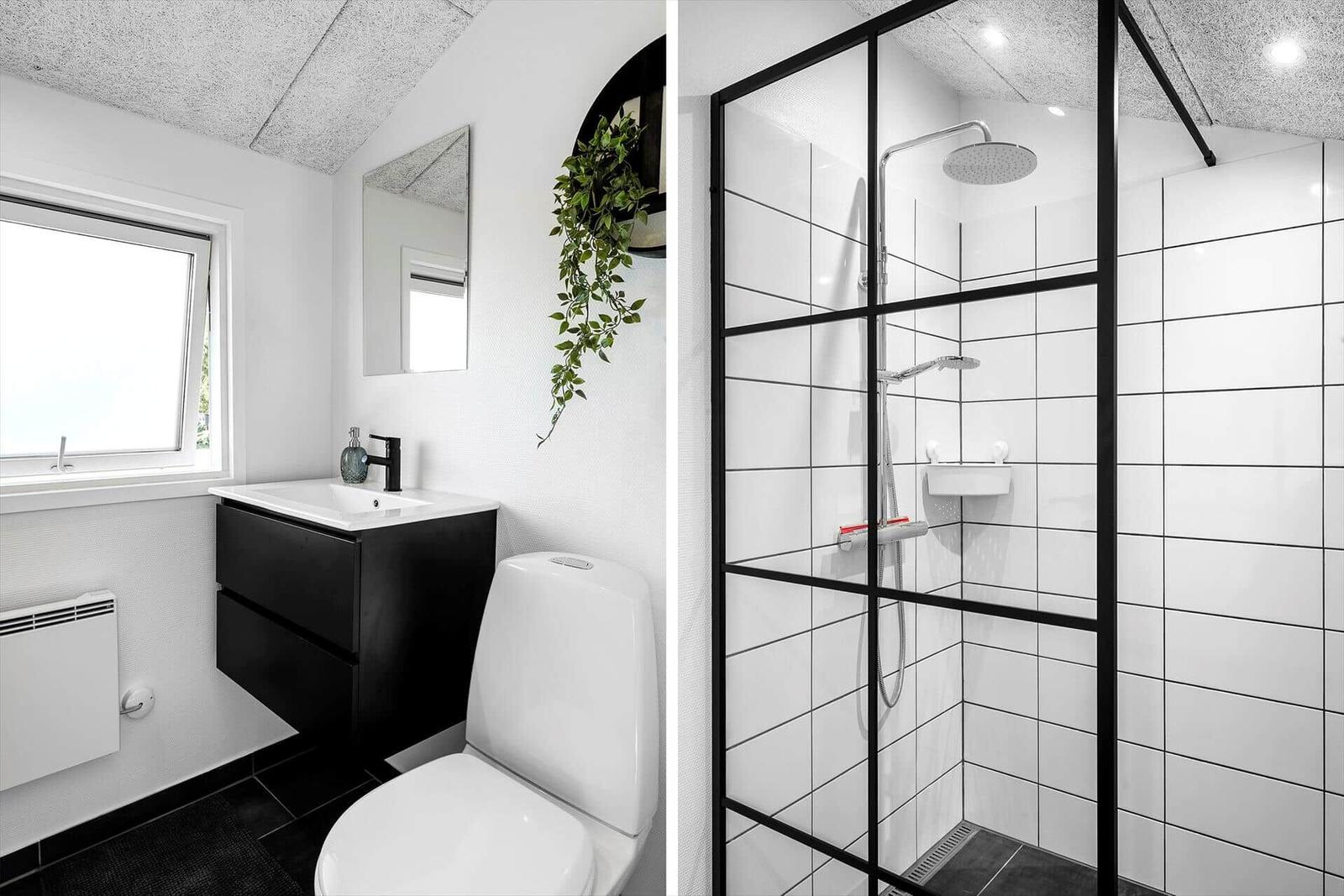 Bathroom with shower, sink and toilet. White tiles and black fixtures.