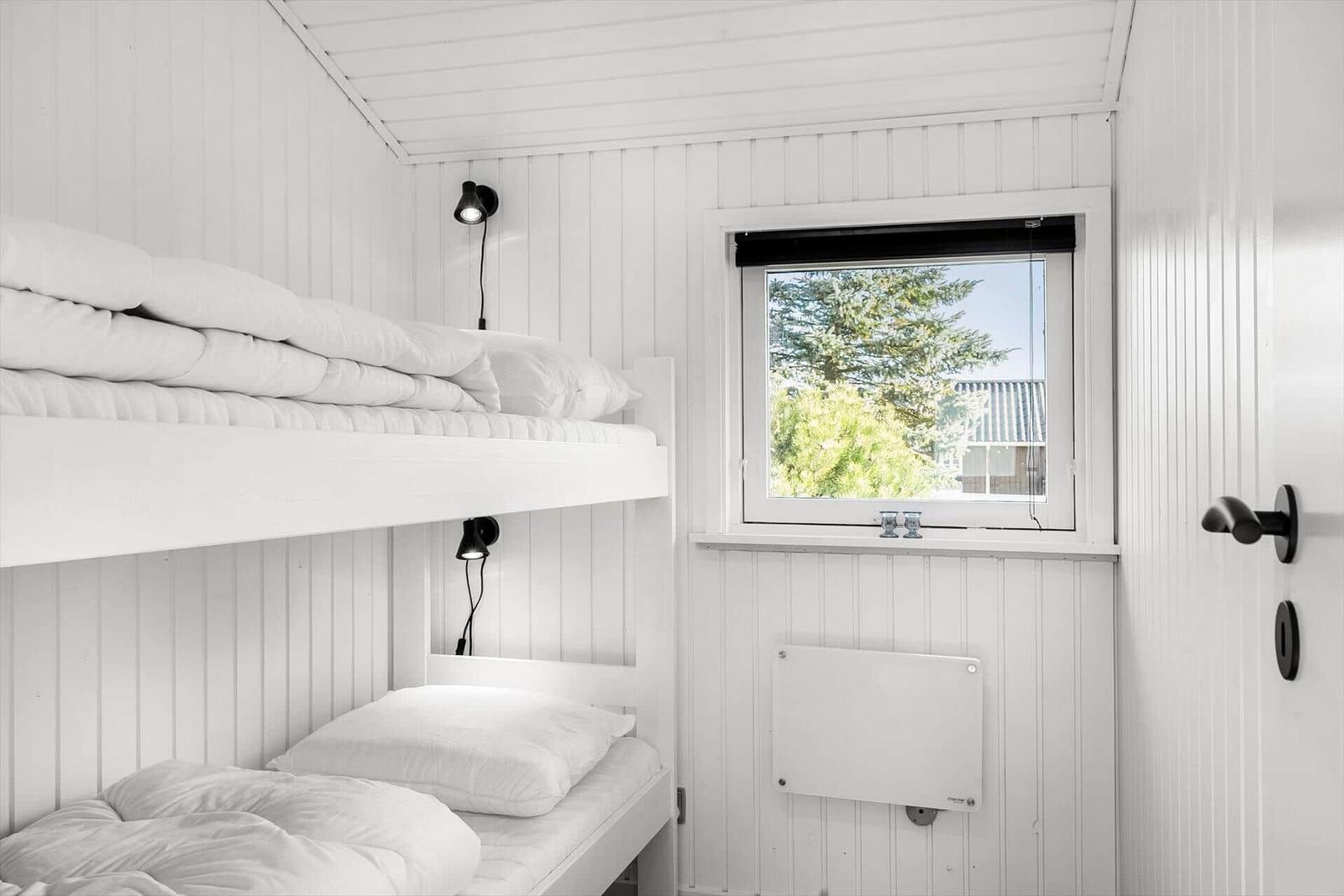 Room with bunk bed, window, and heater.