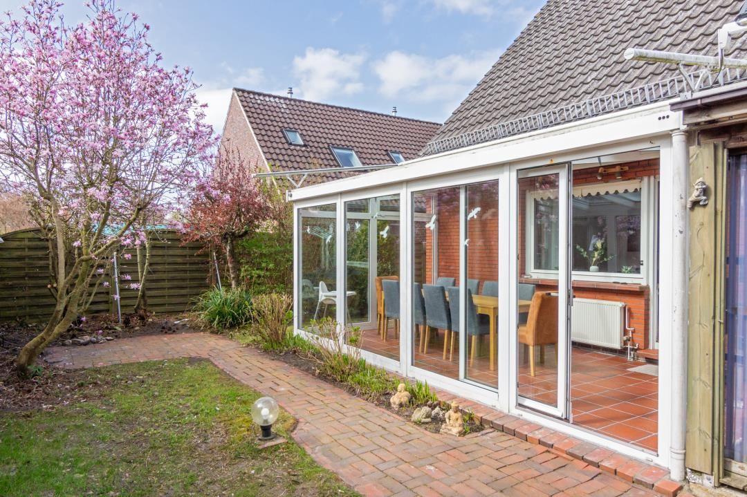 Terrasse mit Sitzgelegenheiten und Blick auf Garten mit blühendem Baum.
