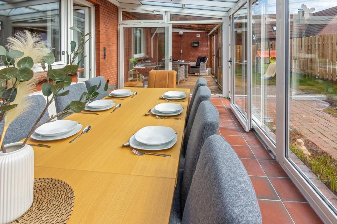 Esstisch mit sechs Stühlen im Wintergarten mit Blick auf den Garten.