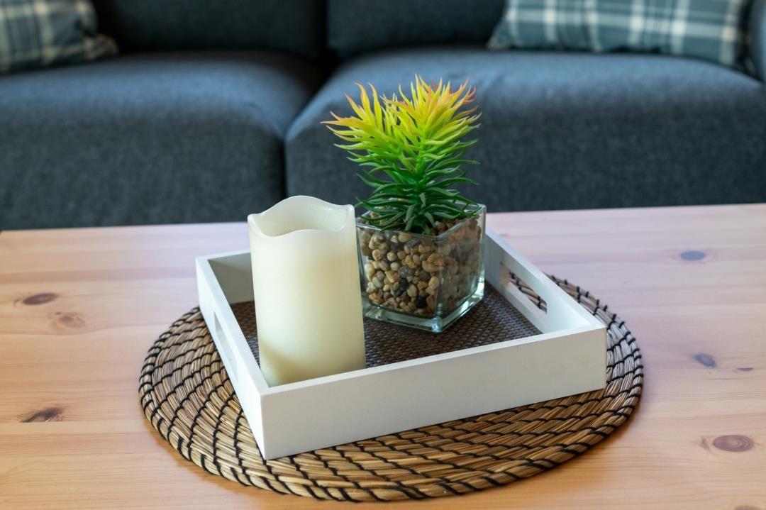 Auf dem Tisch steht ein weißer Kasten mit einer Pflanze und einer Kerze.
