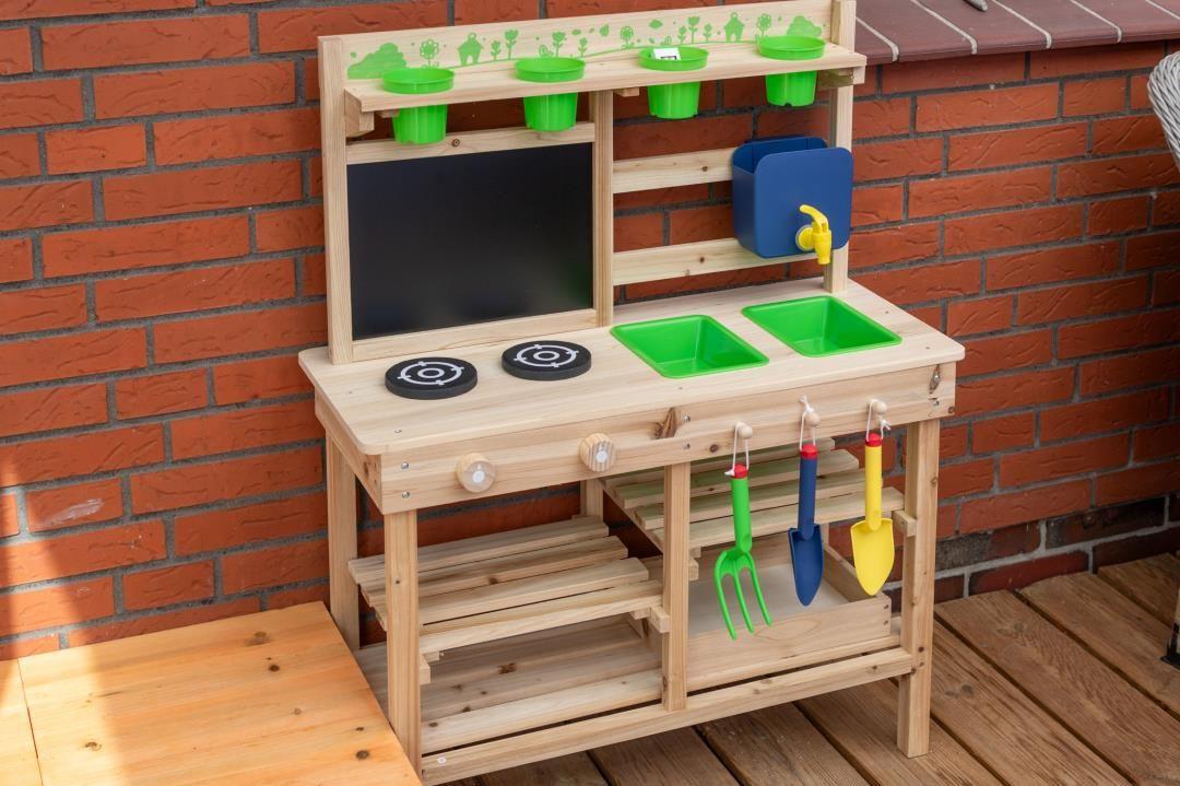 Holzspielküche mit grünen Becken und bunten Werkzeugen an der Wand.