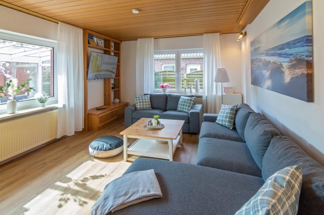 Wohnzimmer mit Sofa, Couchtisch und Fenstern.