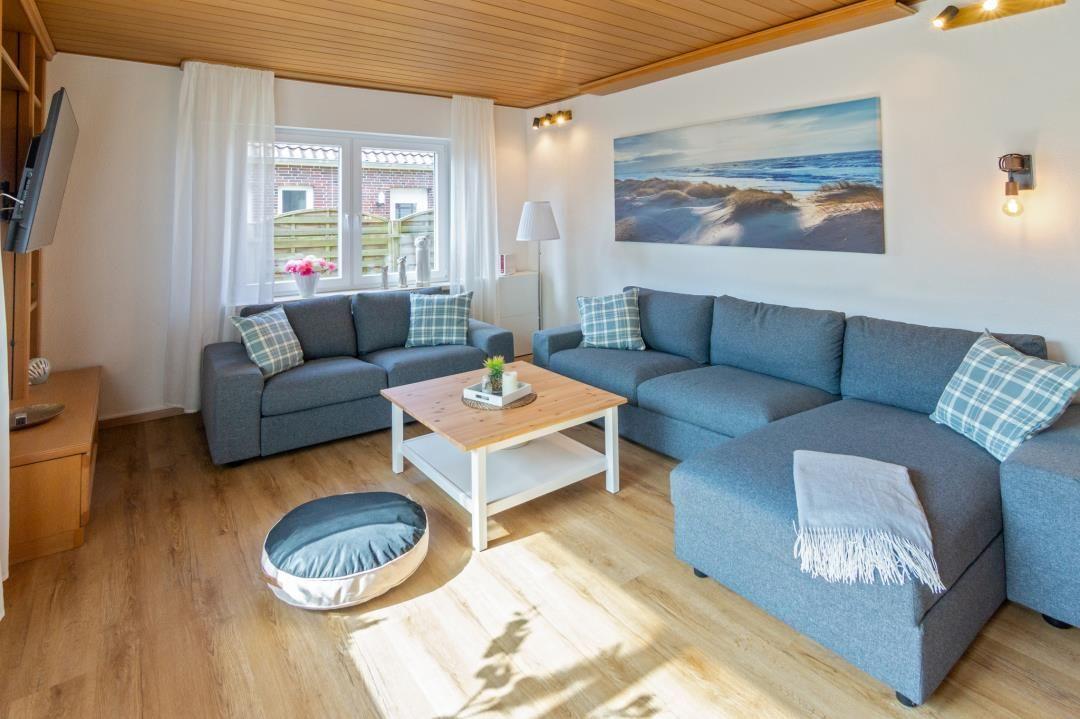 Wohnzimmer mit blauem Sofa, Holztisch und Fensterblick