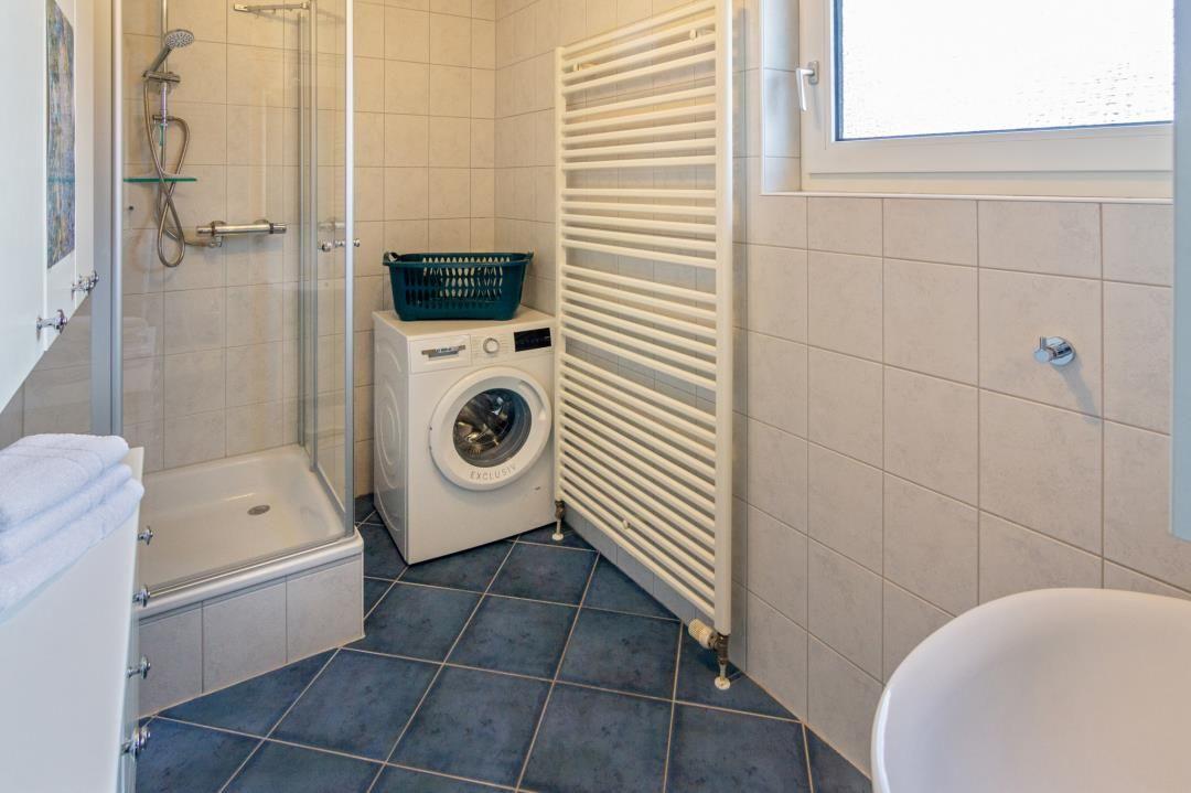 Badezimmer mit Dusche, Waschmaschine und Heizkörper