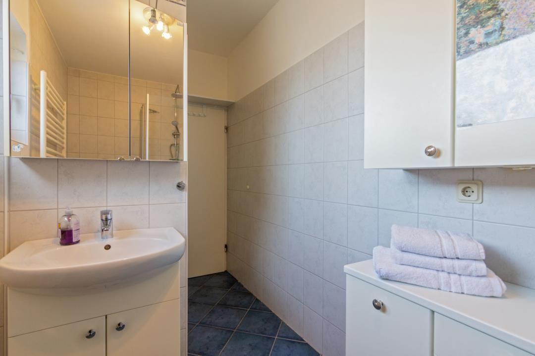 Badezimmer mit Waschbecken, Spiegel, Dusche und Handtüchern.