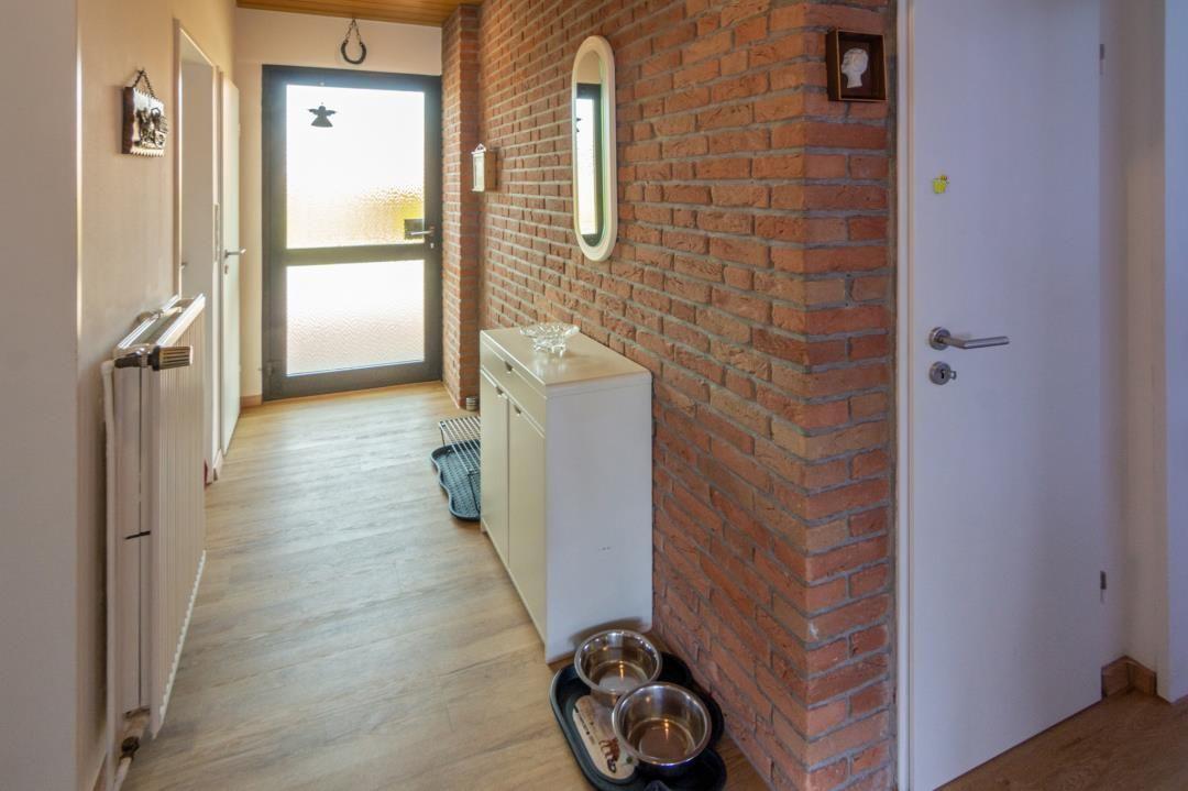 Flur mit Backsteinwand, weißem Schrank und Hundefutterstation