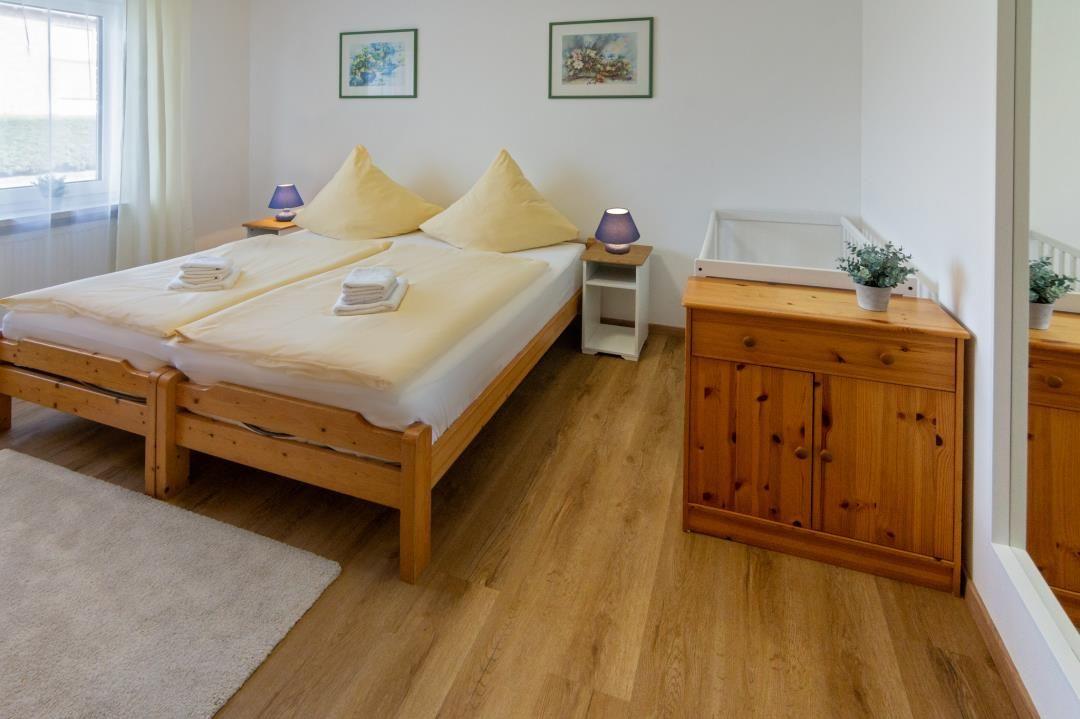 Ein Schlafzimmer mit Doppelbett, Holzmöbeln und Fenster.