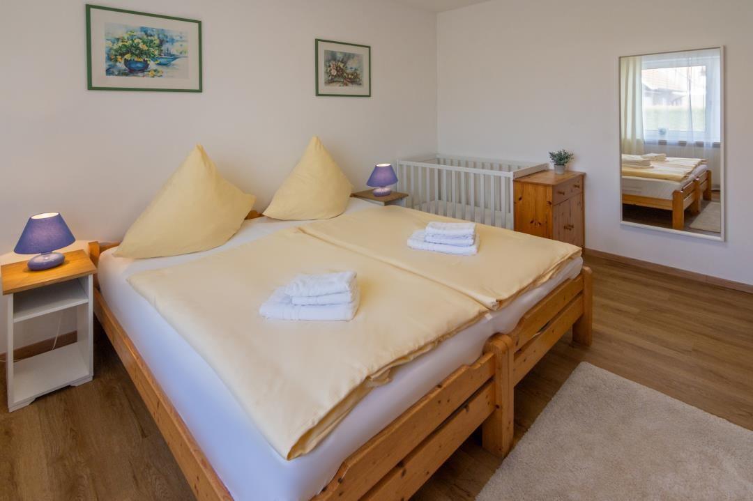 Ein Schlafzimmer mit Holzbett, zwei Nachttischen und einem Kinderbett.