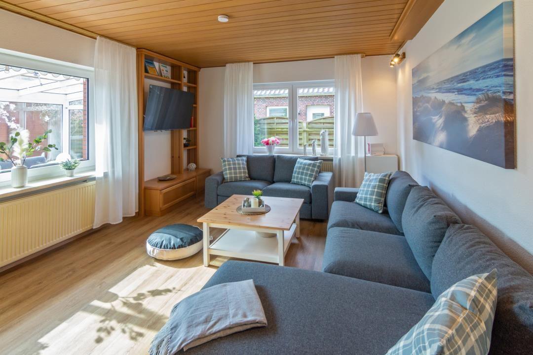 Wohnzimmer mit Sofa, Couchtisch und Fernseher an der Wand.