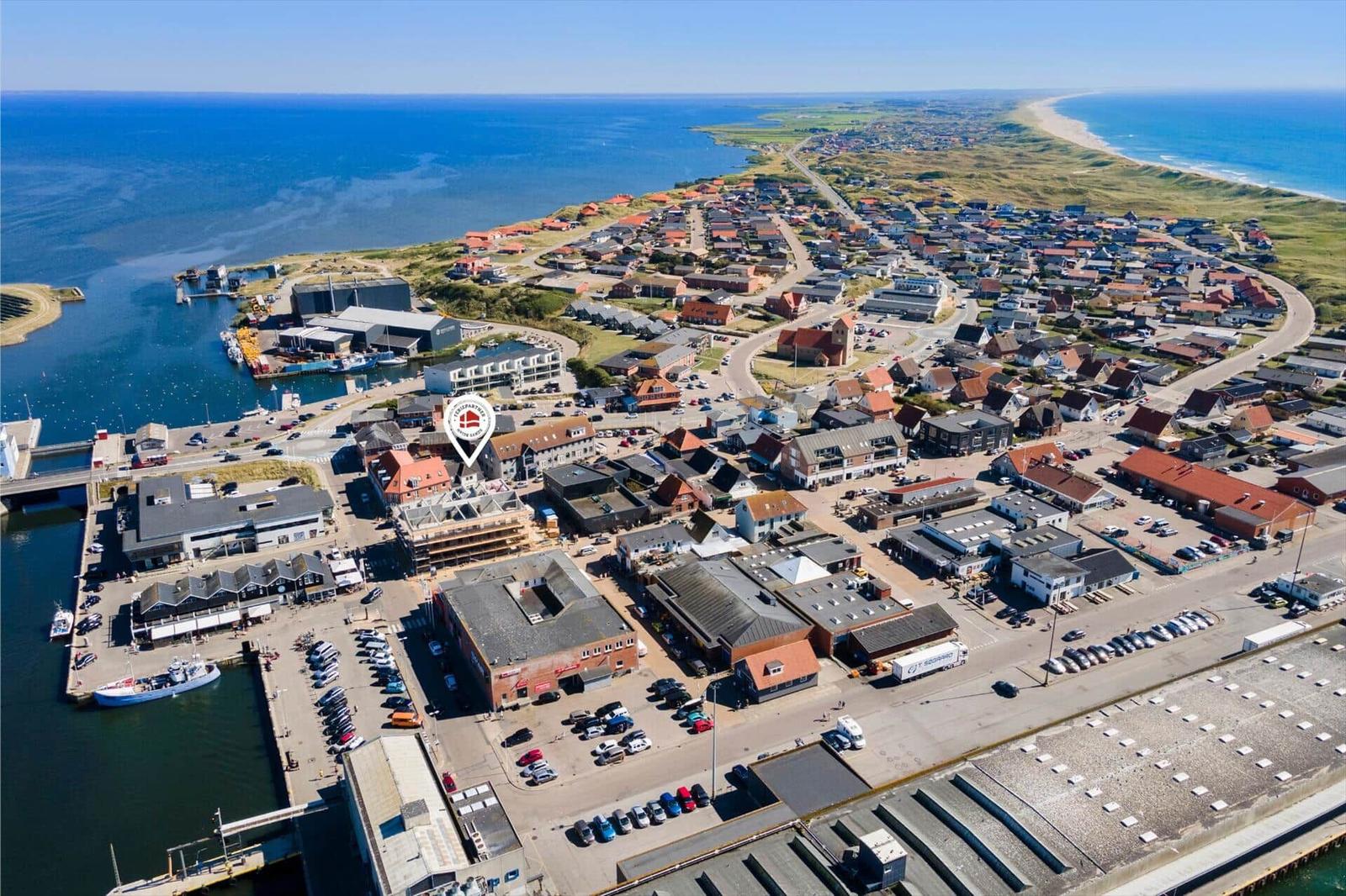 Aerial view of coastal town with harbor, beach, and buildings.