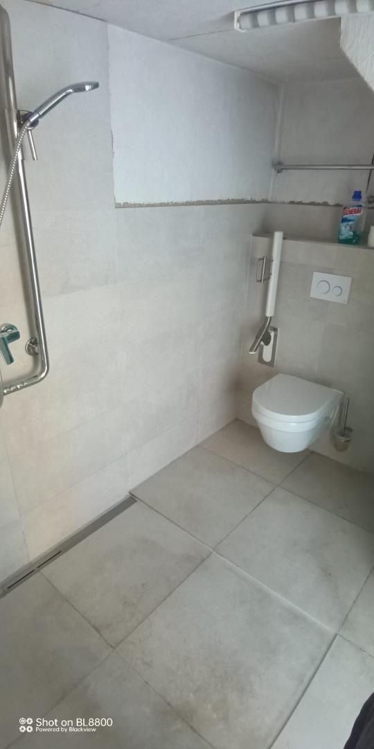 Badezimmer mit Dusche, WC und Handtuchhalter.