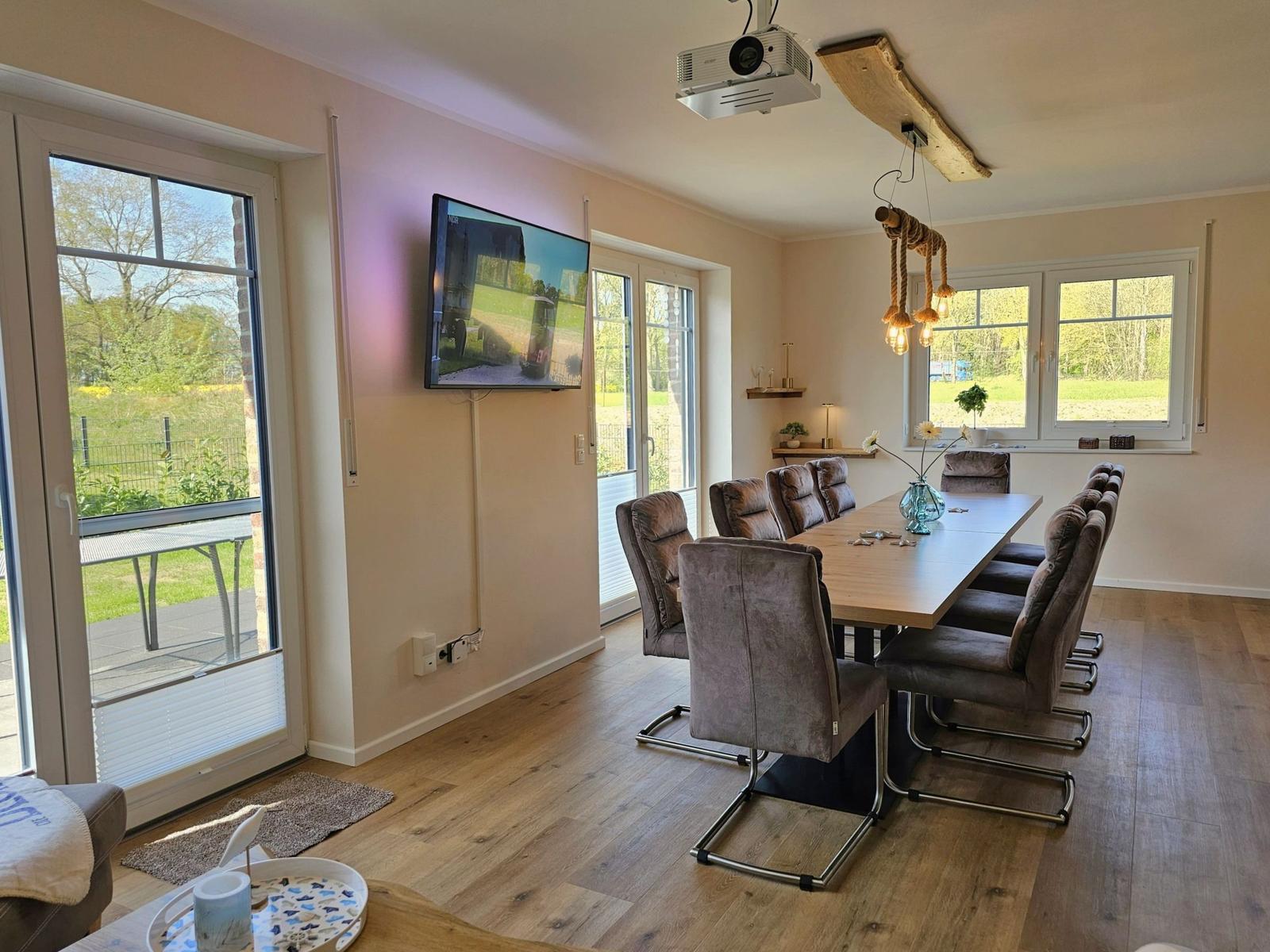 Esszimmer mit Langtisch, Stühlen und Fenstern zum Garten