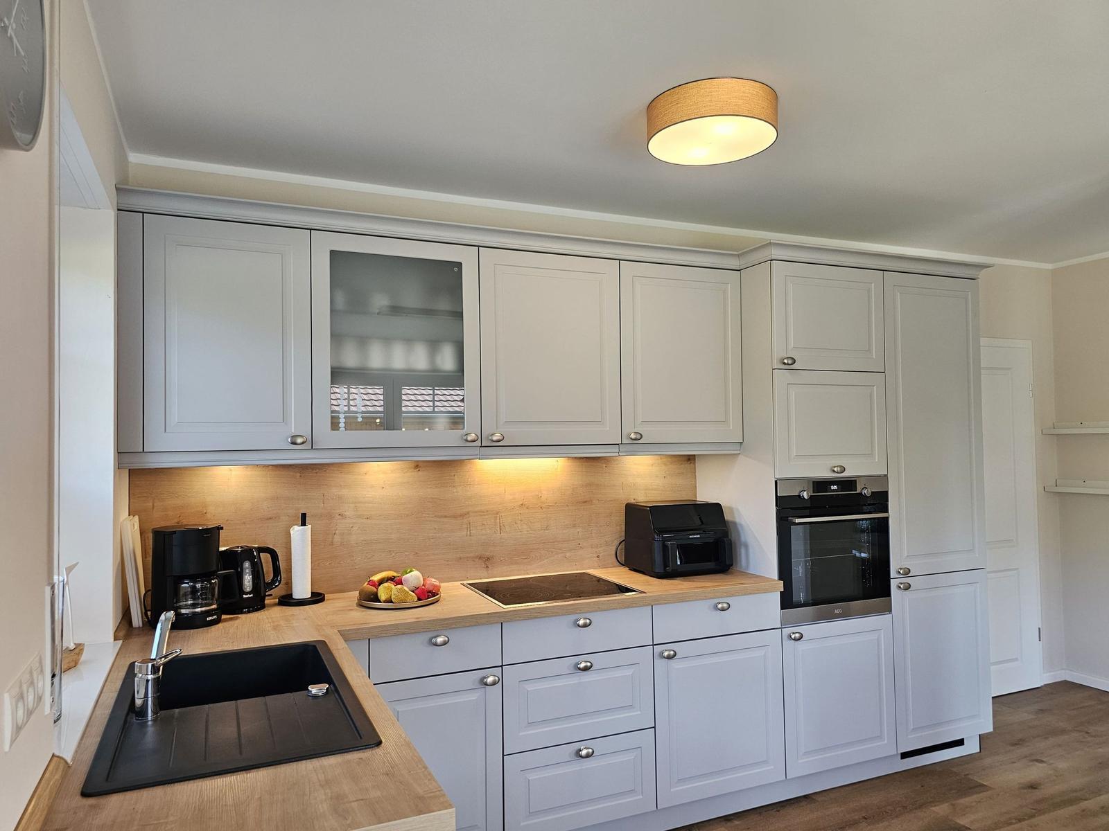 Küche mit hellen Schränken, Holzoberfläche und integriertem Ofen.