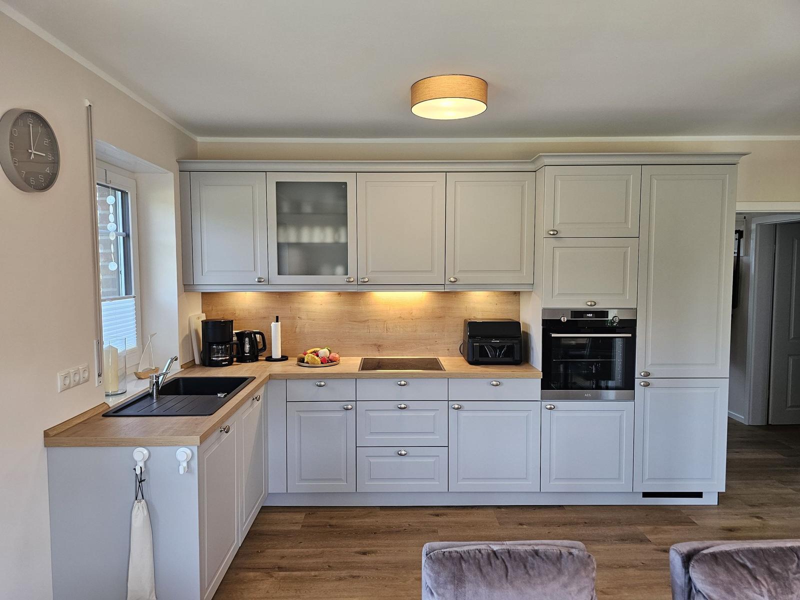 Küche mit hellen Schränken, Holzoberfläche und integriertem Backofen.