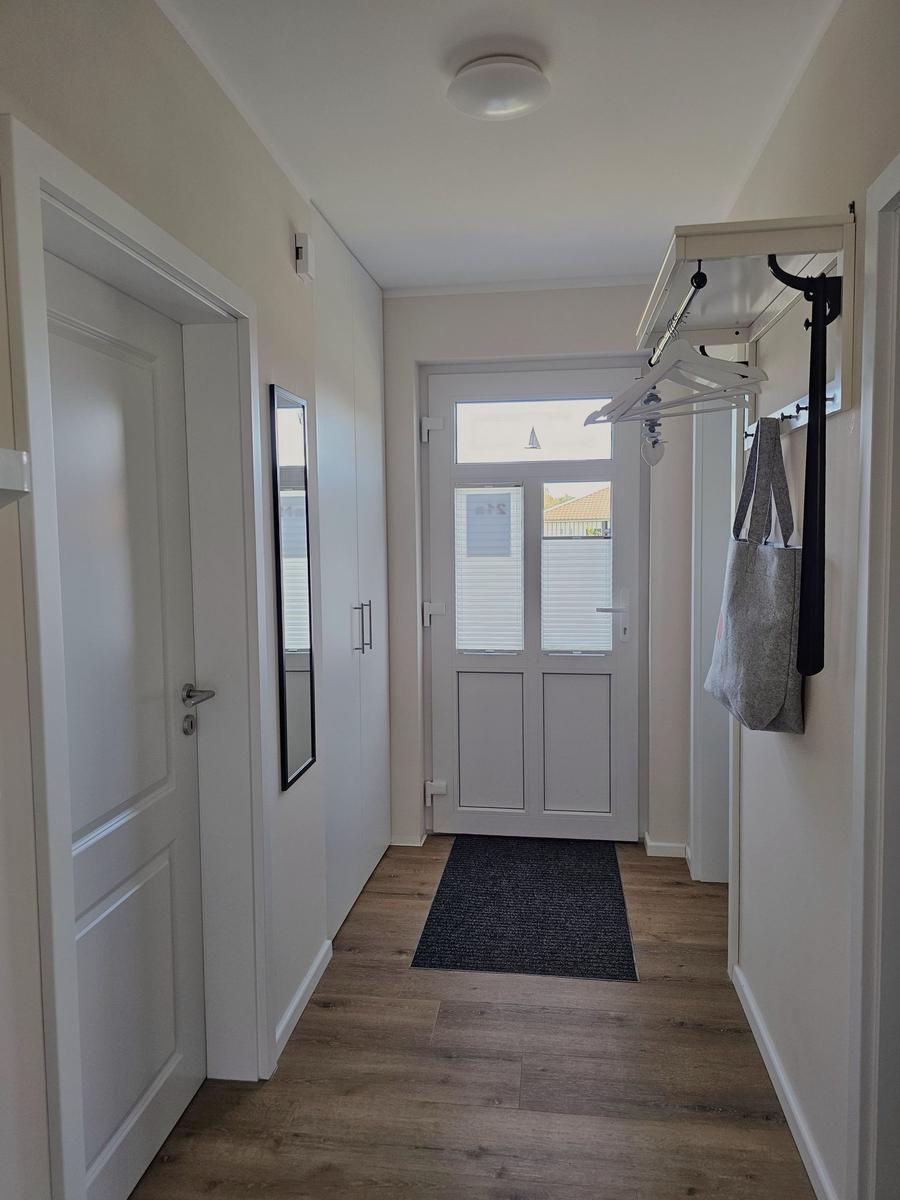 Flur mit Holzboden, Tür und Kleiderständer an der Wand