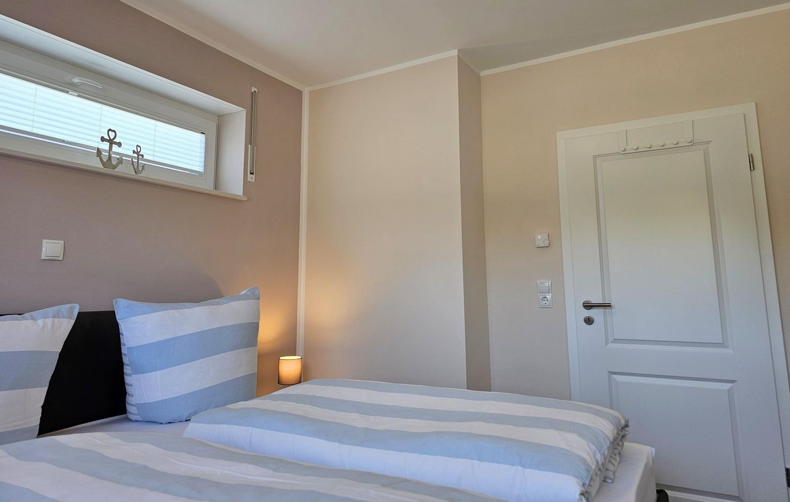 Schlafzimmer mit Bett, Fenster und Tür