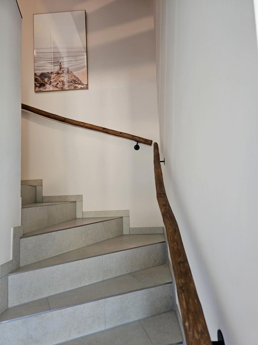 Treppe mit Holzgeländer und Wandbild an der Wand