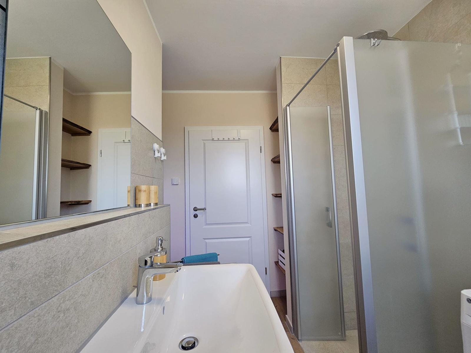 Bad mit Dusche, Waschbecken und Spiegel