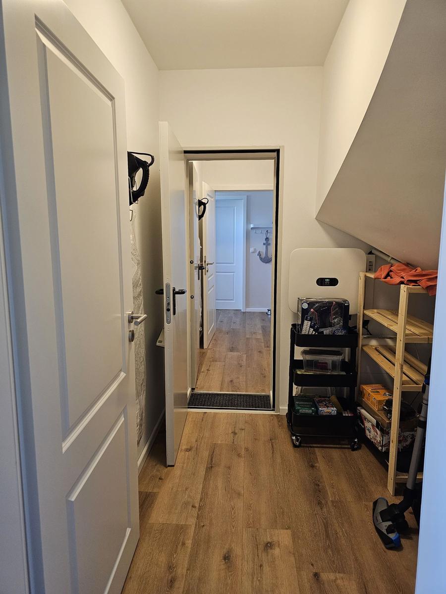 Flur mit Holzboden, Tür und Regal unter Dachschräge.